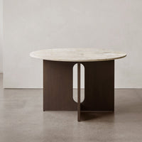 Round marble-top table with a sleek dark wood base featuring a modern cutout design. Neutral colors and smooth textures.