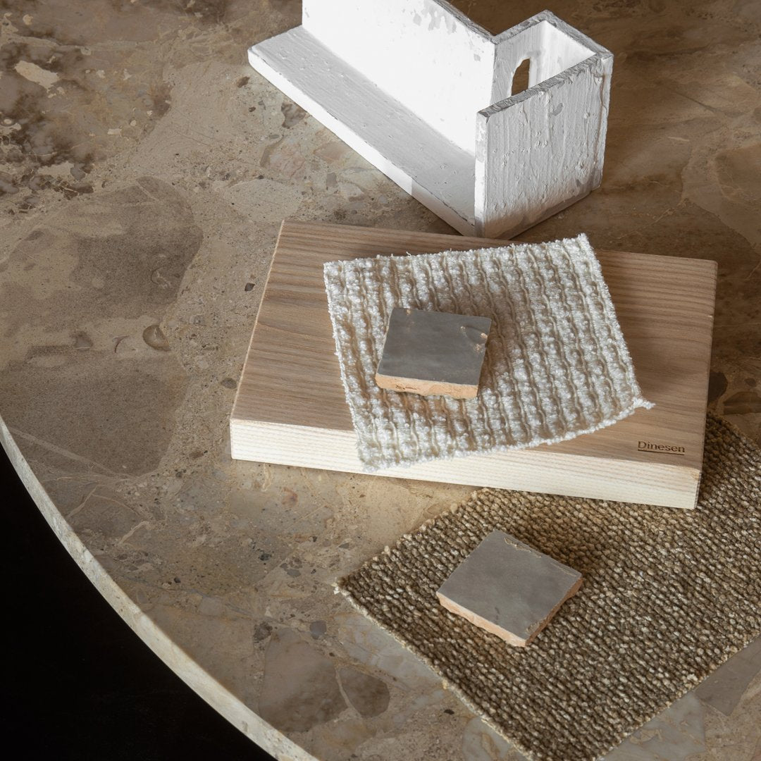 Natural wood textures with a white woven cloth, metallic accents, and a soft beige surface pattern.