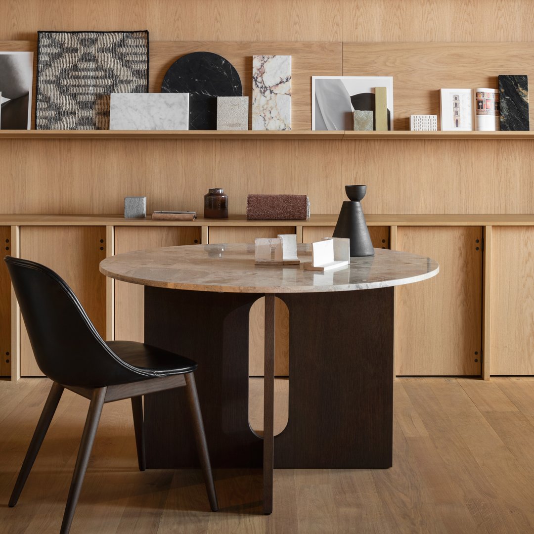 Round marble-top table with dark wood base, featuring neutral colors and minimalist patterns against a wooden backdrop.