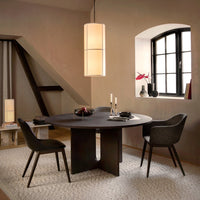 Modern round black dining table with dark chairs on a light textured rug, soft beige walls, and warm ambient lighting.