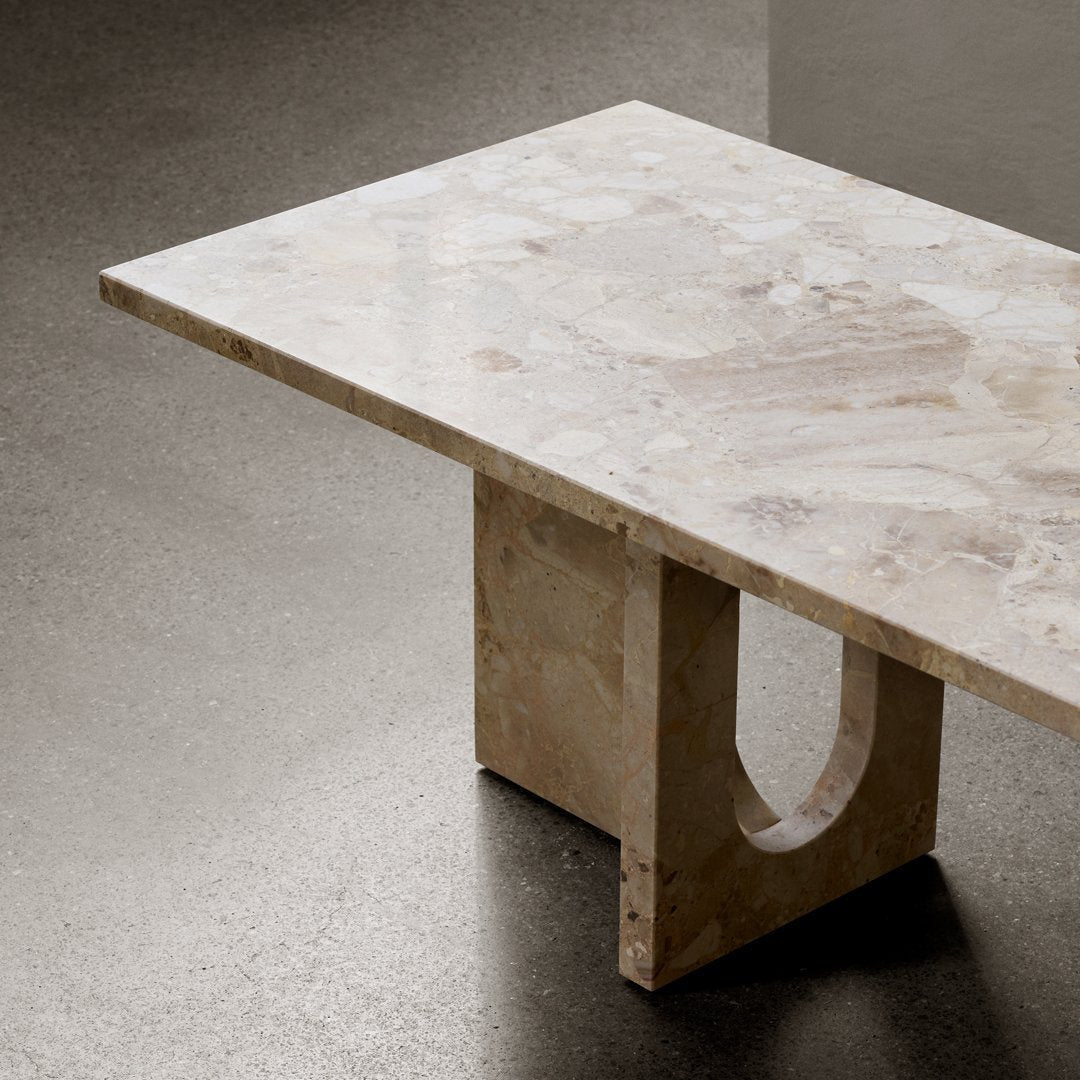 Light beige stone tabletop with subtle marbling patterns and a beige geometric base. Modern minimalist design.