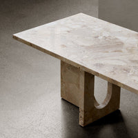 Light beige stone tabletop with subtle marbling patterns and a beige geometric base. Modern minimalist design.
