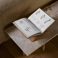 Open book on marble table featuring minimalist black-and-white illustrations, soft beige background, and natural textures.