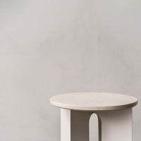Minimalist round table in soft beige with a smooth surface and subtle curves, perfect for modern decor.