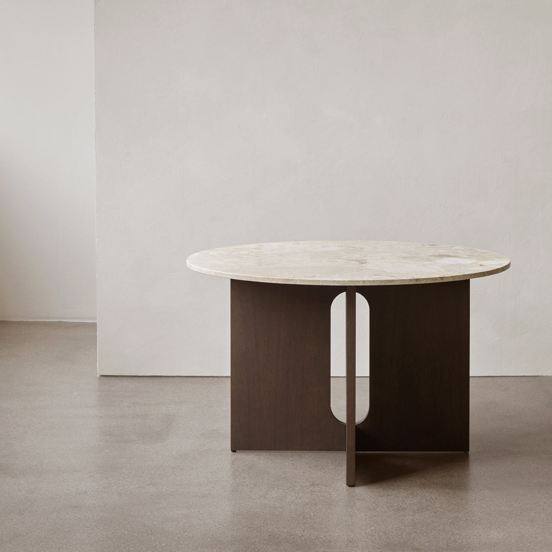 Round marble top table with a dark wood base featuring a circular cutout, showcasing a modern minimalist design.
