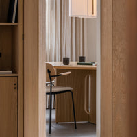 Modern office with neutral tones, warm wood textures, soft fabric curtains, and a minimalist chair design.
