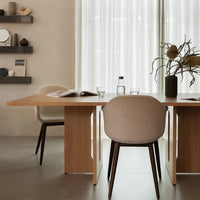 Minimalist dining setting with warm wooden tones, beige chair upholstery, and soft, neutral curtains.