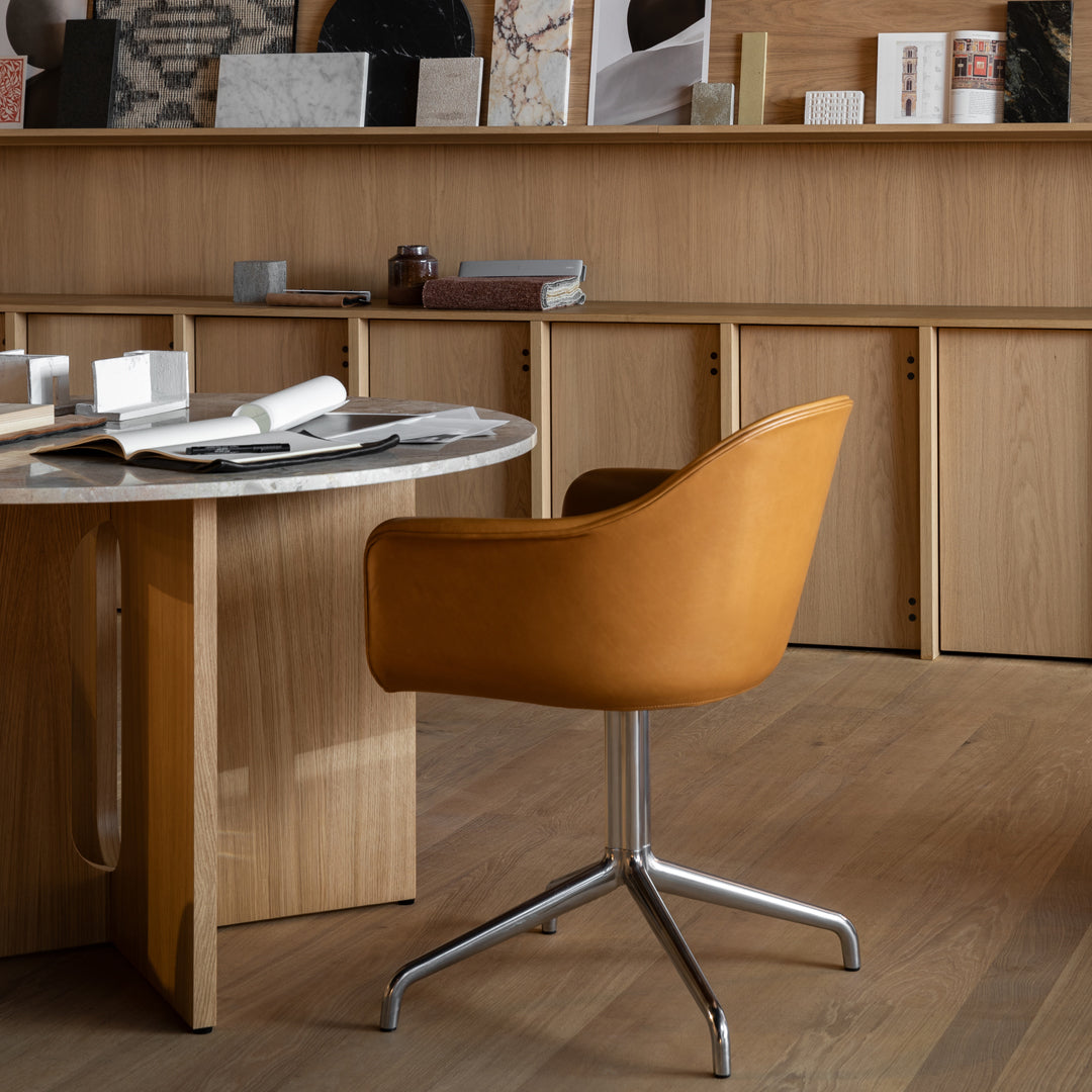 Stylish orange leather chair with a sleek chrome base, set against a warm wooden backdrop. Perfect for modern decor.