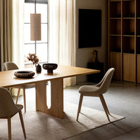 Modern dining table with light oak finish, soft beige chairs, and neutral-toned decor in a warm, inviting space.