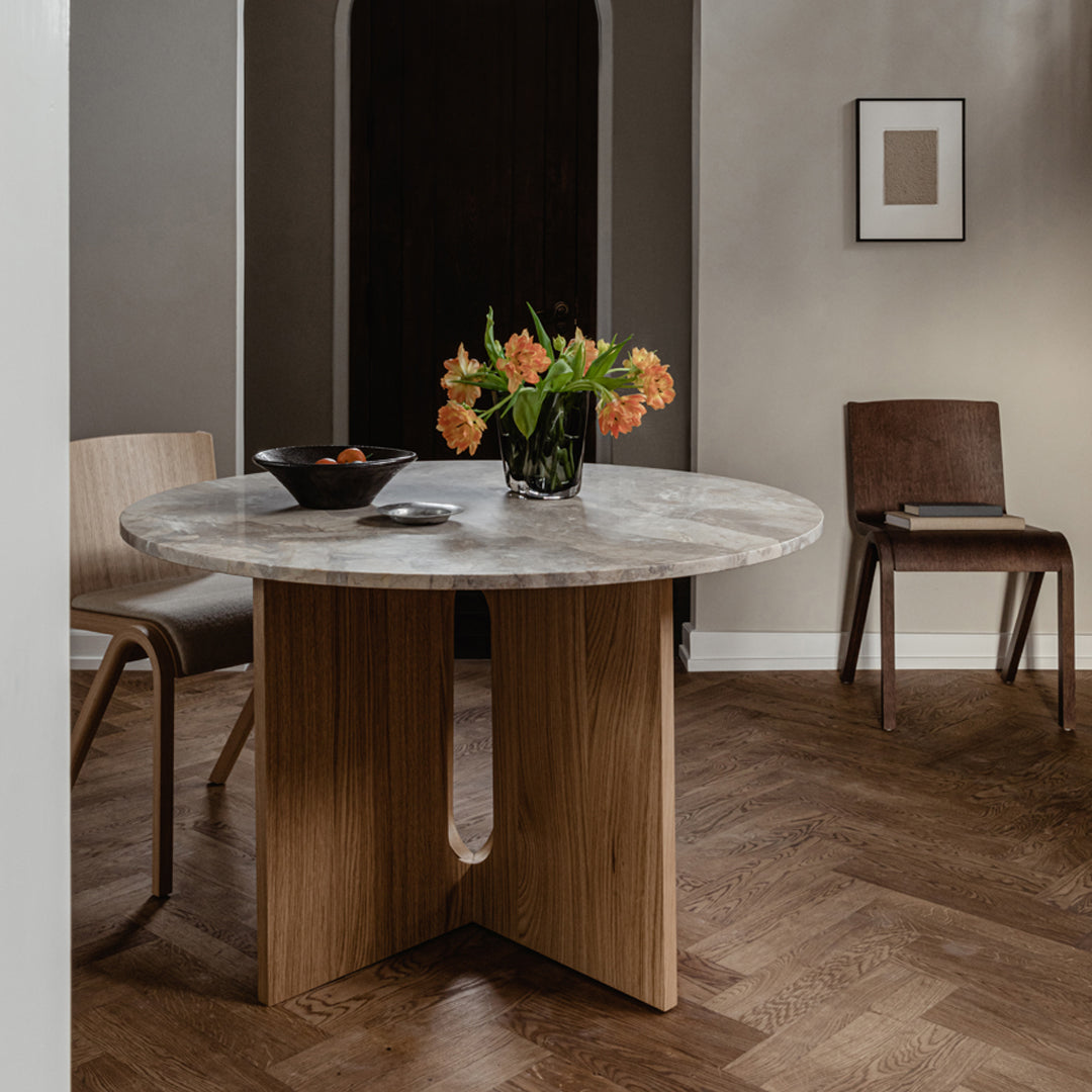 Round marble table with a natural wood base, featuring soft gray and creamy white hues, set against a warm brown floor.