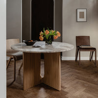 Round marble table with a natural wood base, featuring soft gray and creamy white hues, set against a warm brown floor.