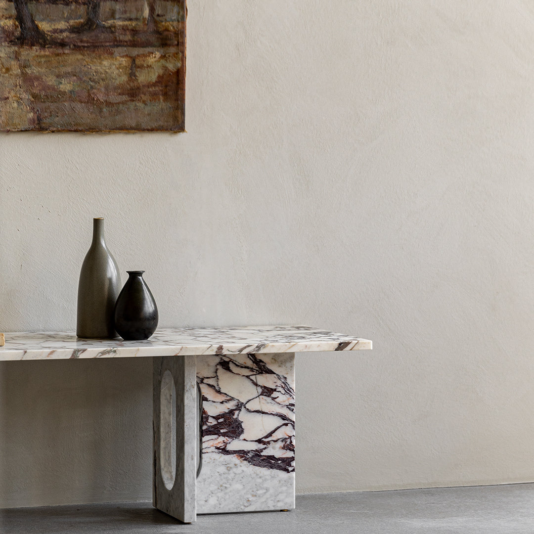 Marble table with elegant gray and white patterns, featuring dark brown veining and minimalist vases in muted tones.