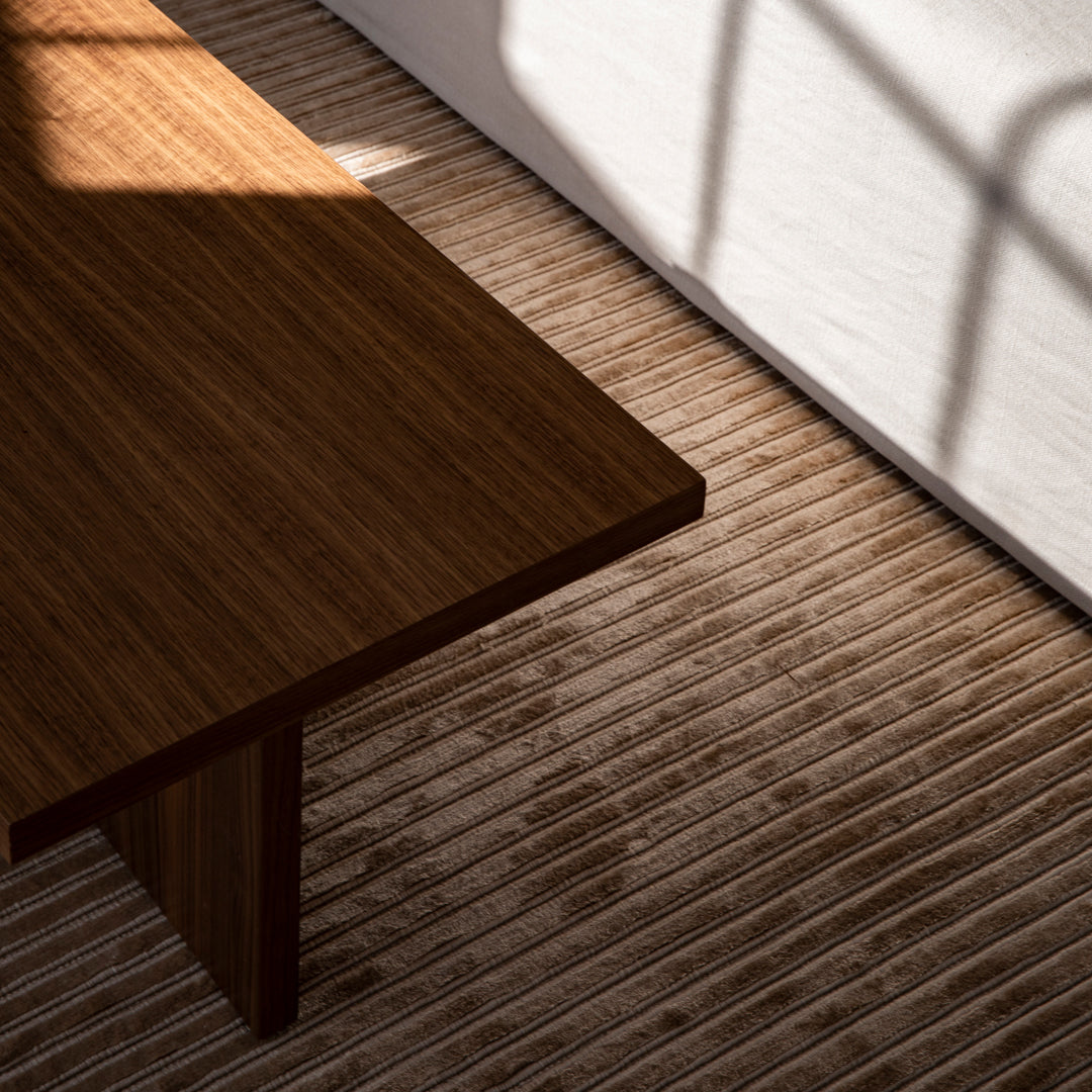"Rich brown wooden table atop textured beige striped flooring with soft shadows."