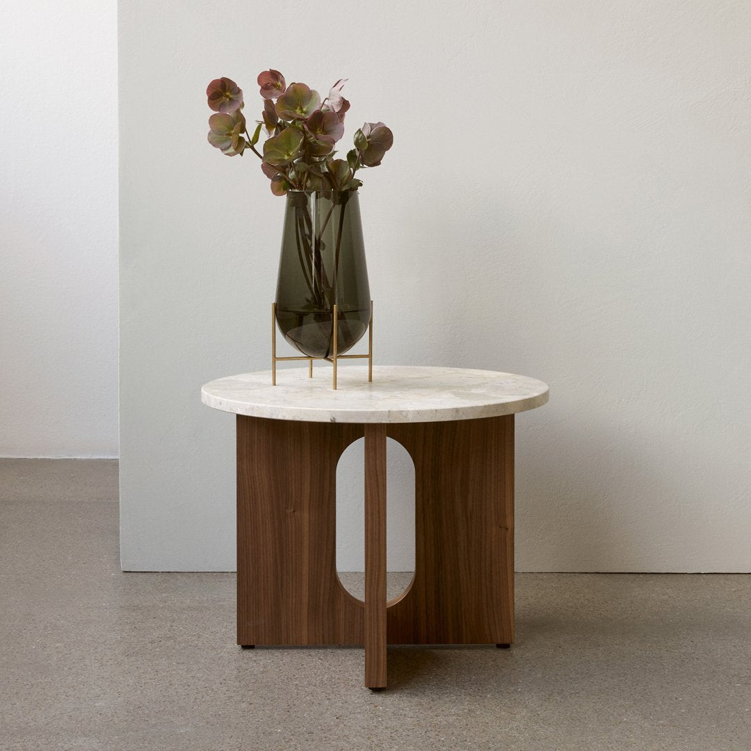 Modern round table with a white marble top and walnut wood base, featuring a minimalist design and soft color palette.