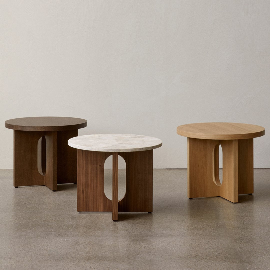 "Modern round tables in dark wood, light wood, and marble tops with sleek cutout designs, perfect for contemporary decor."