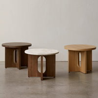 "Modern round tables in dark wood, light wood, and marble tops with sleek cutout designs, perfect for contemporary decor."