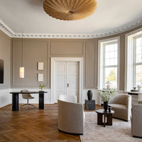 Contemporary living room featuring warm beige walls, light wood flooring, and minimalist furniture in soft neutral tones.