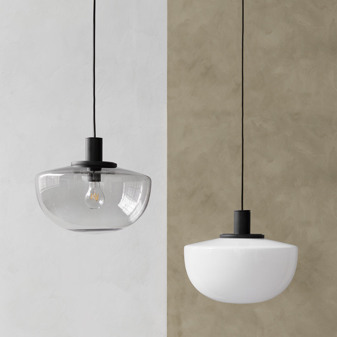 Two pendant lights: one clear glass, one white opaque, both with black metal accents. Modern and minimalist design.