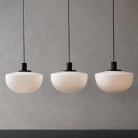 Three rounded frosted white glass pendant lights with sleek black metal fixtures, creating a modern and minimalist aesthetic.