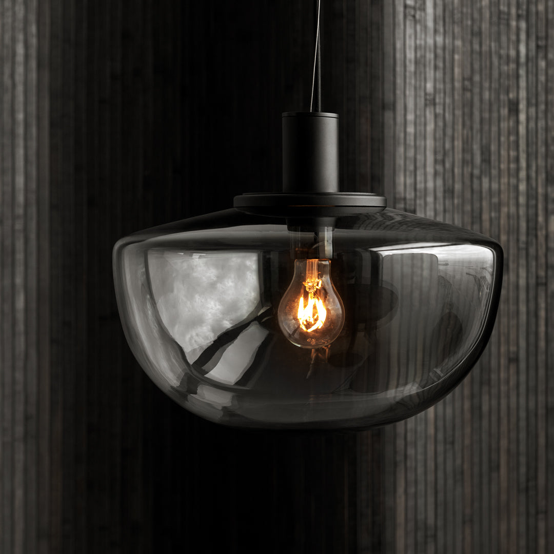 Stylish black glass pendant light with a warm amber bulb, perfect for modern decor.