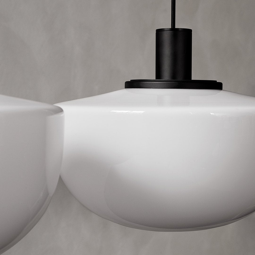 White glossy pendant lamp with sleek black accents against a textured gray background.