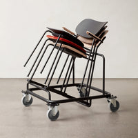 Stacked chairs in black, gray, and red hues on a wheeled cart, showcasing a modern design with minimalistic patterns.