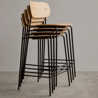 Stacked chairs featuring light wood seats and sleek black metal frames against a neutral backdrop.