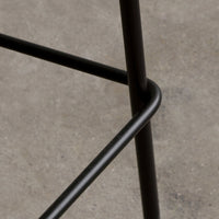 Black metal frame with smooth curved lines, set against a gray concrete background. Modern design minimalism.