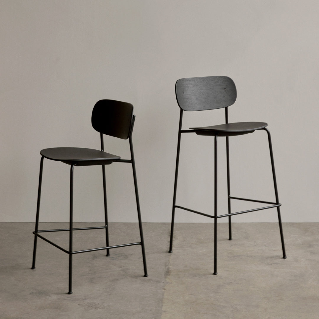 Two modern bar stools in matte black with minimalist design, featuring sleek lines and a subtle textured finish.