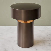 Round dark bronze table with a gold accent, featuring a modern minimalist design and smooth surfaces.
