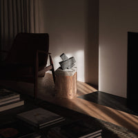 Black geometric shapes on a white base, with soft shadows and natural wood tones in a modern setting.