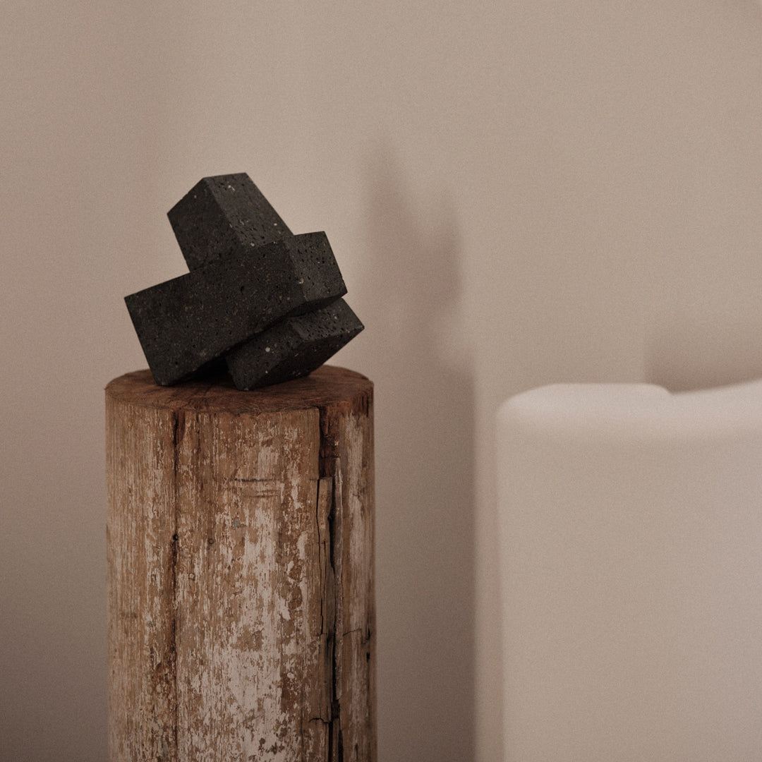 "Black geometric decor on a rustic wood stump against a soft neutral background."