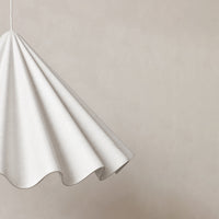 White patterned hanging lamp against a subtle beige background, showcasing elegant, flowing fabric design.