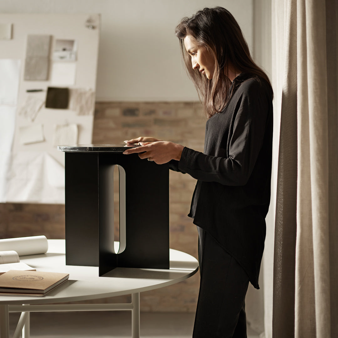 Sleek black stool on a white table, showcasing a modern design with clean lines and minimalistic style.
