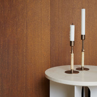 "Elegant white candle holders with cream accents against a rich brown textured background."