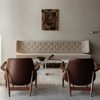 Beige tufted sofa, rich brown leather chairs, and neutral textured rug create a modern, chic living space.