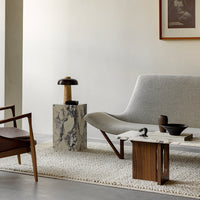Gray upholstered chair, marble side table with white and gray veining, brown wood accents, and neutral rug.