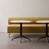 Yellow upholstered sofa with smooth white tabletops and minimalist black legs on a neutral background.