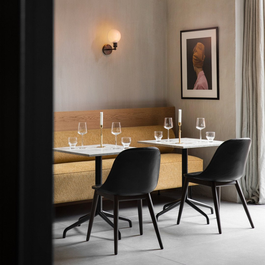 Modern dining setup with earthy tones, black chairs, and elegant glassware against a soft gray backdrop.