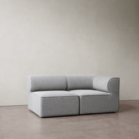Gray upholstered sectional sofa with a minimalist design, featuring smooth lines and a modern aesthetic.
