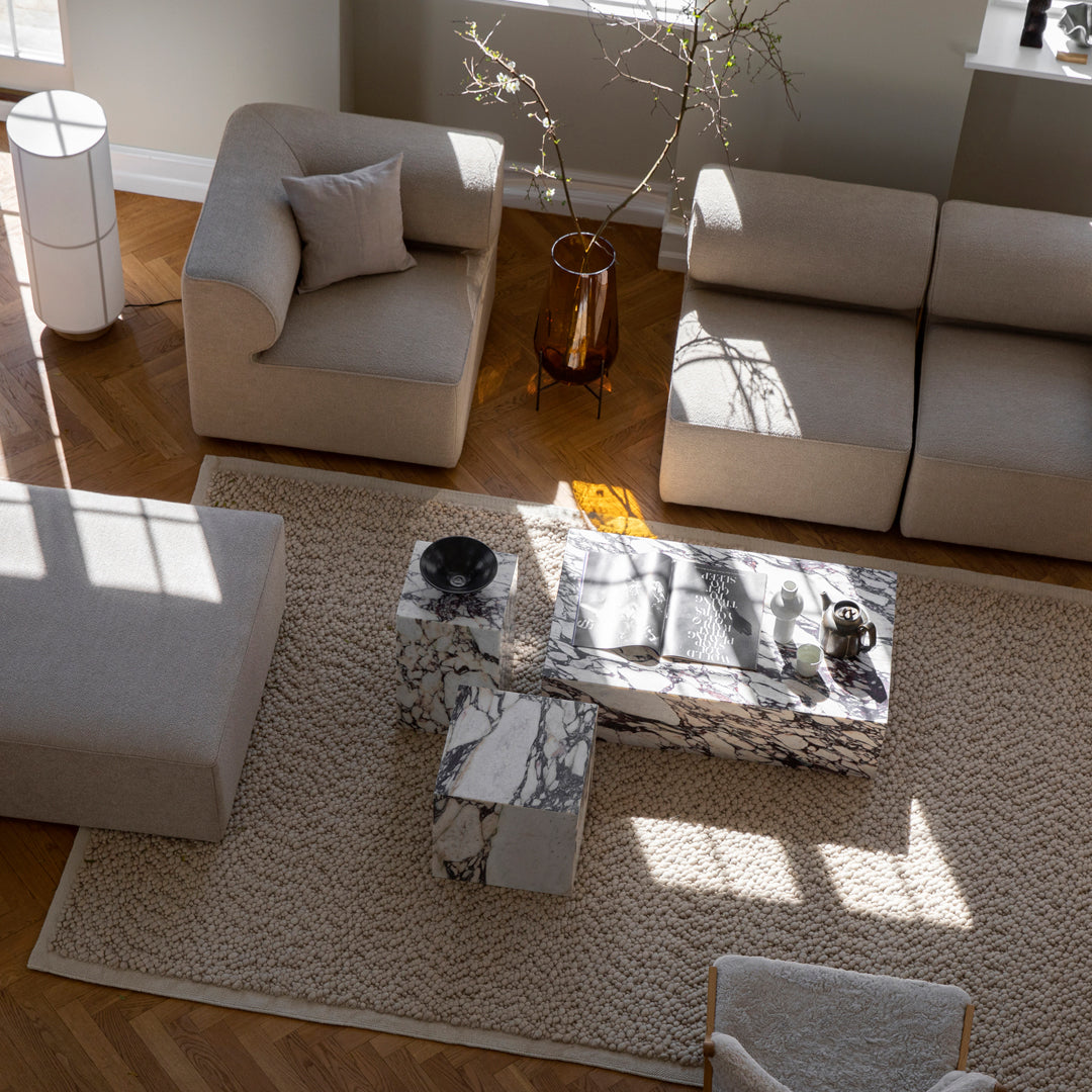 Beige and cream sofa set with a marble-patterned coffee table on a textured cream rug, accented by natural wood tones.