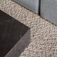 Gray textured rug with a woven pattern, paired with a sleek black marble surface. Modern and stylish design elements.