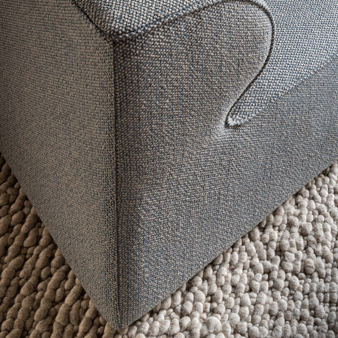 Gray textured upholstery with subtle patterns, paired with a neutral woven rug.
