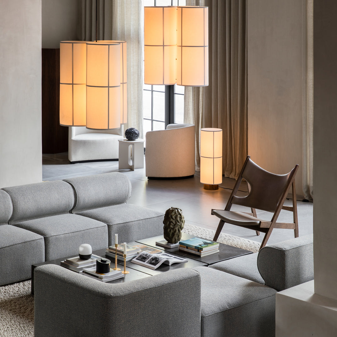 Modern gray sectional sofa with clean lines, complemented by soft beige and warm lighting elements in a stylish interior.