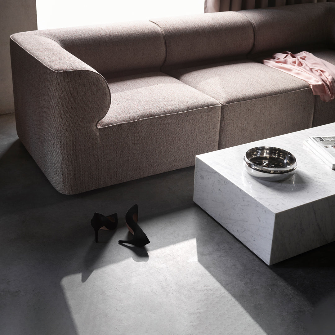 Neutral beige sofa with subtle texture, paired with a sleek white marble coffee table and dark accents.