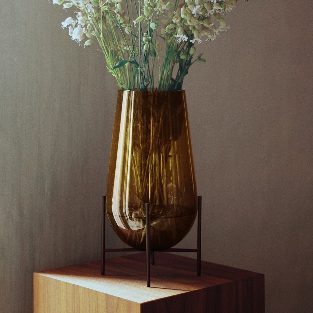 Amber glass vase with a unique shape, showcased on a wooden pedestal, adorned with delicate white flowers.