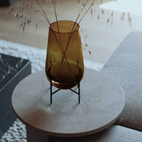 Amber glass vase on a marble table, paired with delicate dried grass decor for a modern, minimalist look.
