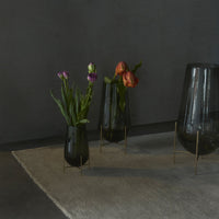 "Elegant black glass vases with vibrant tulips, set against a muted gray background and neutral textured rug."