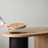 Natural wood grain table with round light oak insert and sleek black base, showcasing elegant color contrast and organic patterns.