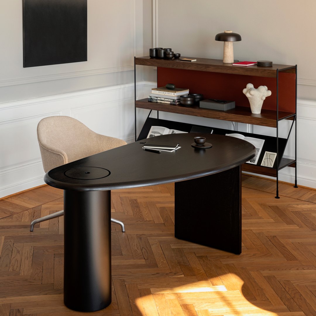 Sleek black desk with a smooth finish, paired with a beige chair and warm wood accents. Stylish modern decor in a minimalist setting.